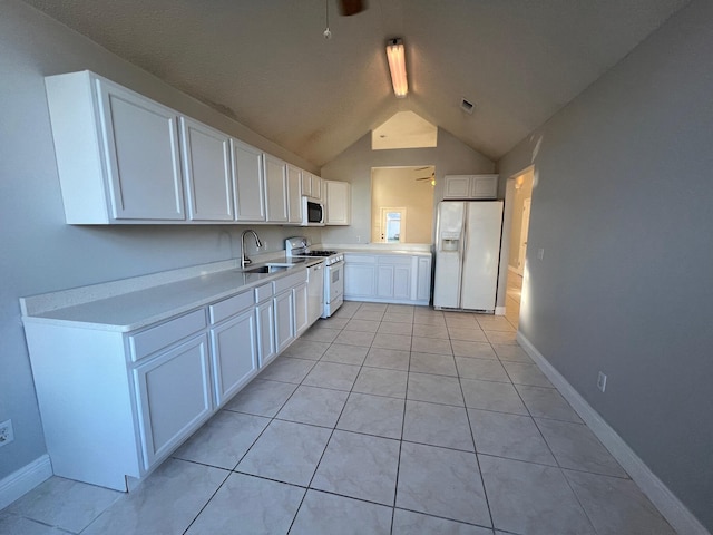 kitchen with lofted ceiling, white appliances, sink, light tile patterned flooring, and white cabinetry