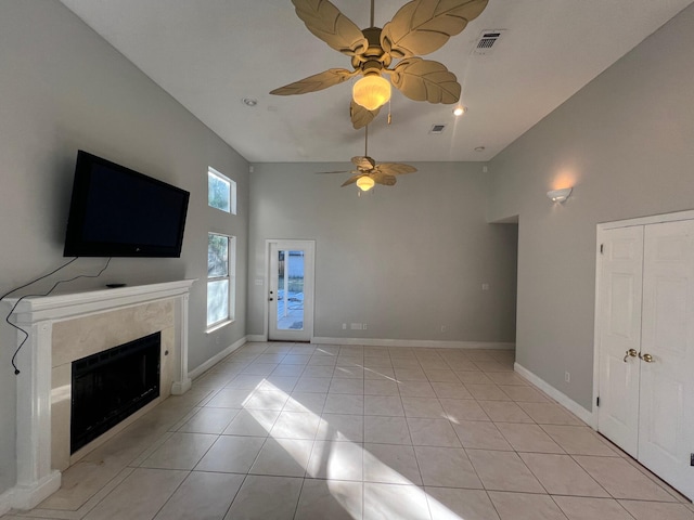 unfurnished living room featuring light tile patterned floors, ceiling fan, and a high ceiling