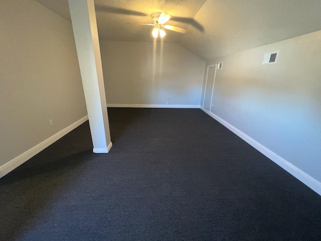 additional living space with dark colored carpet, ceiling fan, a textured ceiling, and vaulted ceiling