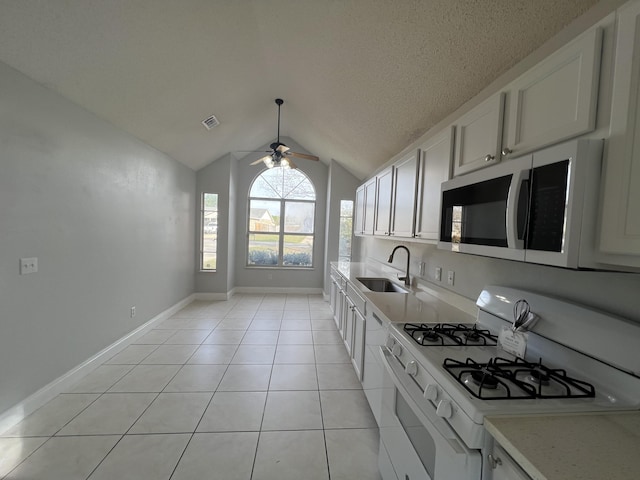 kitchen featuring sink, white cabinetry, vaulted ceiling, ceiling fan, and white appliances