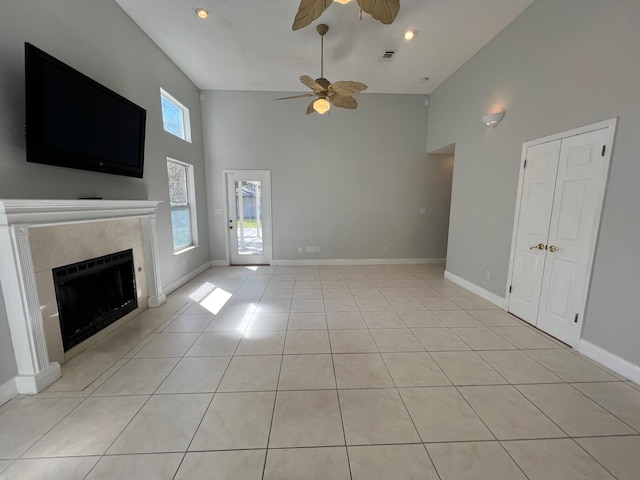 unfurnished living room featuring a ceiling fan, a fireplace, light tile patterned floors, high vaulted ceiling, and baseboards
