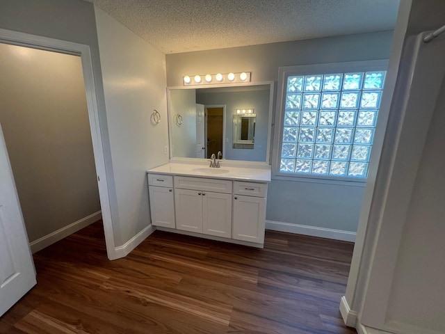 bathroom with baseboards, a textured ceiling, wood finished floors, and vanity
