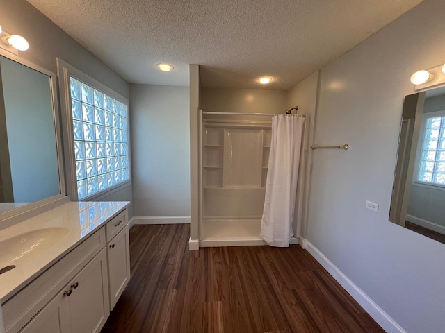 full bath with baseboards, a shower with curtain, a textured ceiling, and wood finished floors