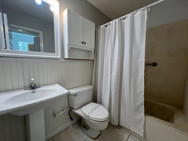 bathroom with a sink, shower / tub combo with curtain, toilet, tile patterned floors, and a textured ceiling