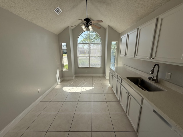 kitchen with a sink, light countertops, a textured ceiling, a ceiling fan, and vaulted ceiling