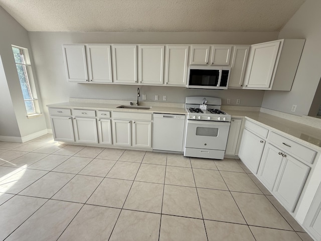 kitchen with white appliances, light tile patterned flooring, a sink, and light countertops