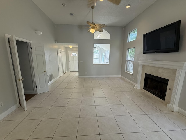 unfurnished living room with ceiling fan, a fireplace, light tile patterned floors, high vaulted ceiling, and baseboards