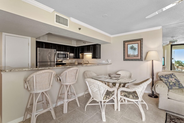 kitchen featuring light stone counters, appliances with stainless steel finishes, kitchen peninsula, and light tile patterned flooring