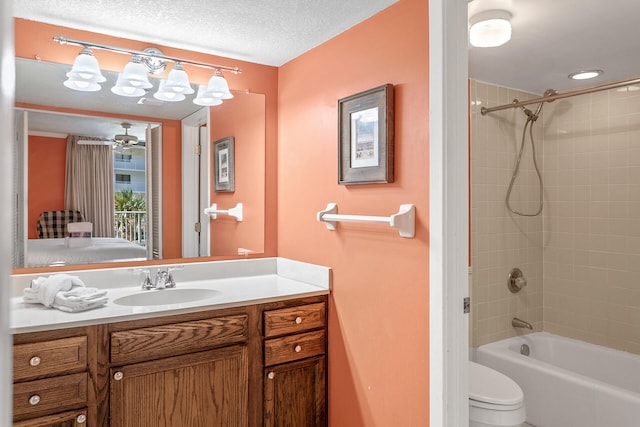 full bathroom with toilet, tiled shower / bath, vanity, a textured ceiling, and ceiling fan