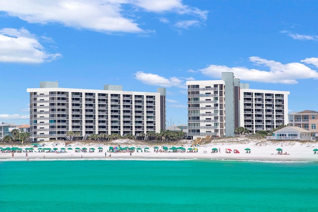 view of building exterior featuring a water view and a beach view