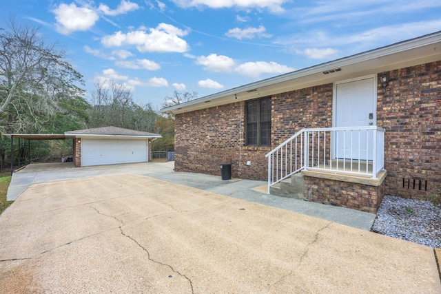 view of property exterior featuring a garage, a carport, brick siding, and an outdoor structure