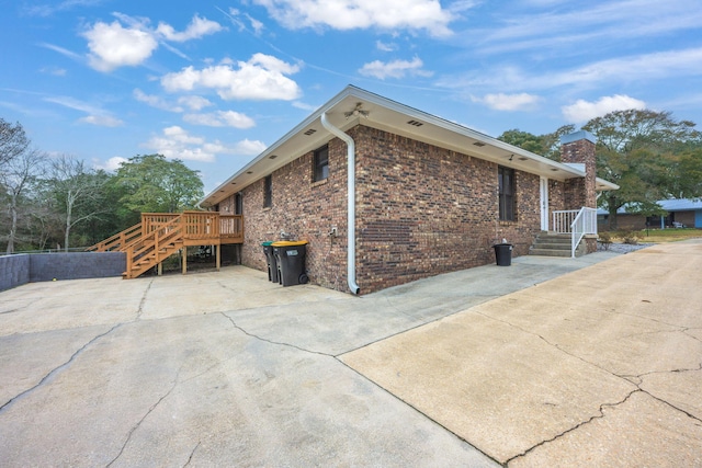 view of property exterior with a wooden deck, stairway, and brick siding