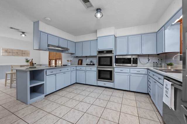 kitchen featuring stainless steel appliances, a peninsula, a sink, visible vents, and light countertops