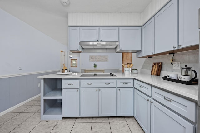 kitchen with a wainscoted wall, black electric cooktop, light countertops, under cabinet range hood, and open shelves