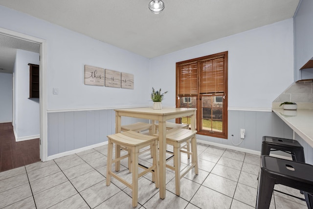 dining space featuring a wainscoted wall and light tile patterned floors