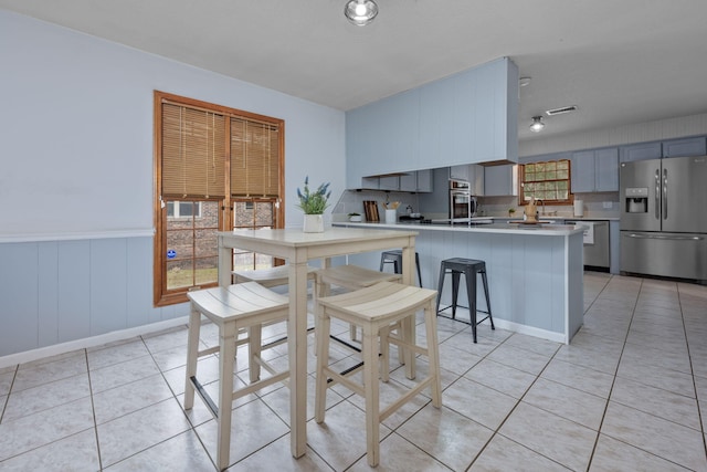 kitchen with light tile patterned floors, a peninsula, appliances with stainless steel finishes, and light countertops