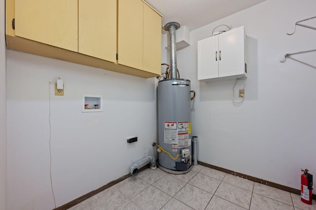 laundry room with cabinet space, light tile patterned floors, baseboards, a textured ceiling, and gas water heater