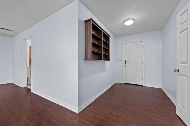 hall featuring baseboards, visible vents, dark wood finished floors, and a textured ceiling