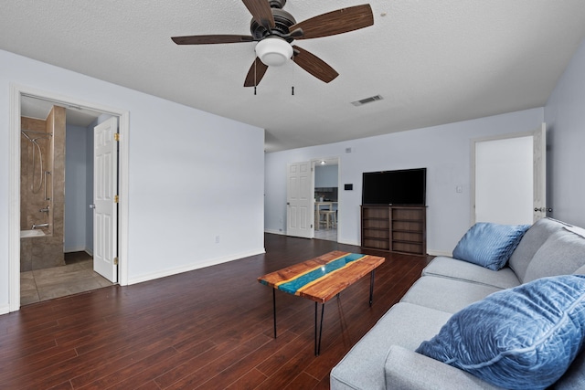 living room with dark wood-type flooring, visible vents, a textured ceiling, and baseboards