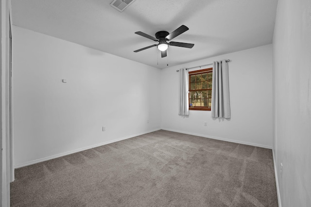 carpeted empty room featuring visible vents, ceiling fan, and baseboards