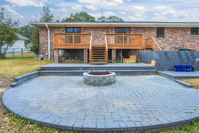 back of property with an outdoor fire pit, stairs, fence, a wooden deck, and a patio area