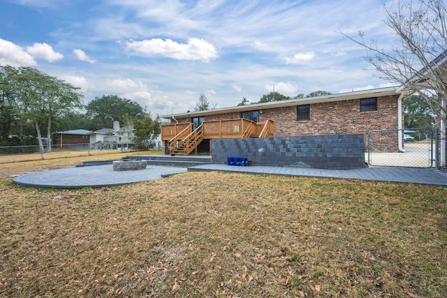 rear view of property with a yard, stairway, an outdoor fire pit, fence, and a deck