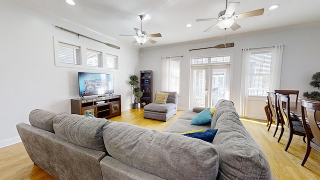 living room with a healthy amount of sunlight, ornamental molding, and light wood-type flooring