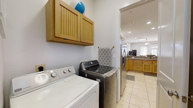 washroom with sink, washing machine and dryer, light tile patterned floors, and cabinets