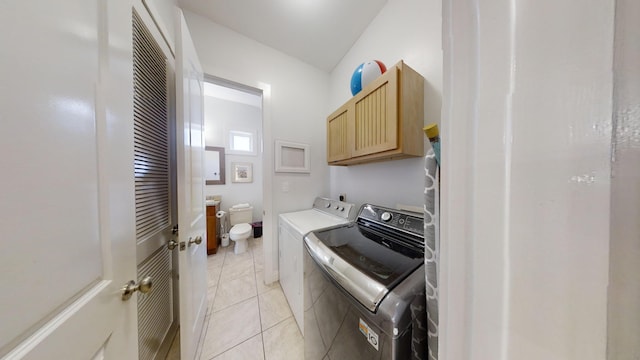 laundry area featuring light tile patterned floors, cabinets, and separate washer and dryer