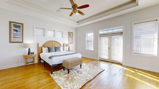 bedroom featuring french doors, ceiling fan, a tray ceiling, and light hardwood / wood-style floors