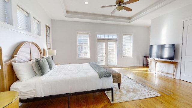 bedroom with wood-type flooring, a tray ceiling, and ceiling fan