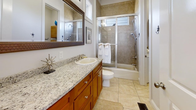 full bathroom with vanity, bath / shower combo with glass door, toilet, and tile patterned flooring