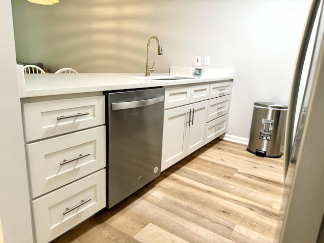 kitchen with sink, dishwasher, white cabinets, and light hardwood / wood-style floors