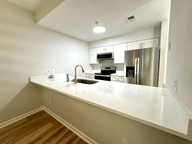 kitchen with sink, kitchen peninsula, stainless steel appliances, white cabinets, and dark wood-type flooring