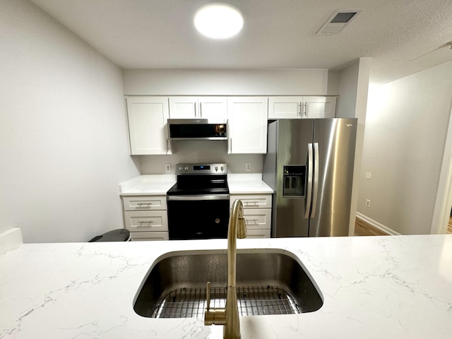 kitchen featuring sink, appliances with stainless steel finishes, and white cabinetry