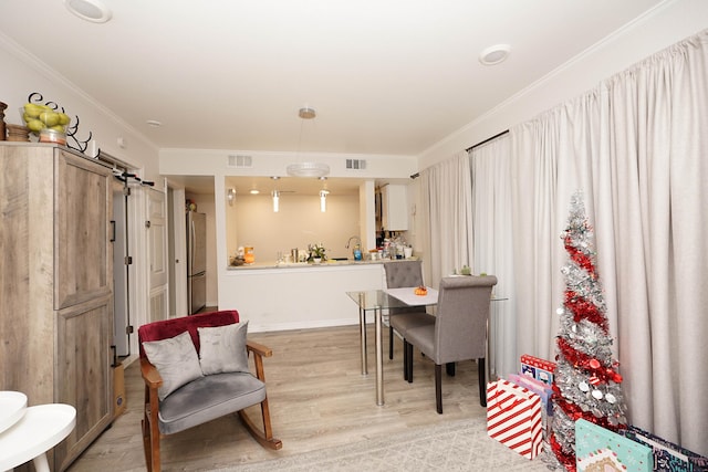 dining space with light hardwood / wood-style floors and crown molding