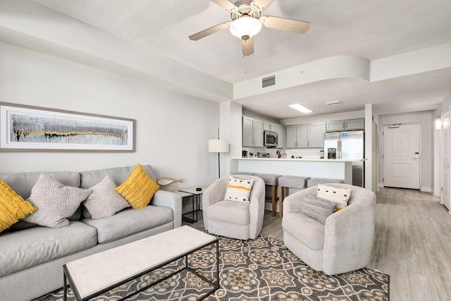 living room with light hardwood / wood-style flooring and ceiling fan