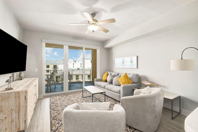 living room with a textured ceiling, light wood-type flooring, and ceiling fan