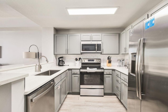 kitchen with sink, gray cabinetry, stainless steel appliances, and light wood-type flooring