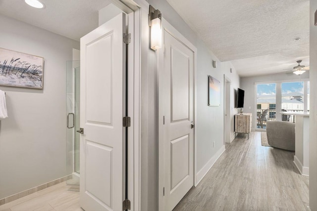 hallway featuring a textured ceiling and light hardwood / wood-style floors