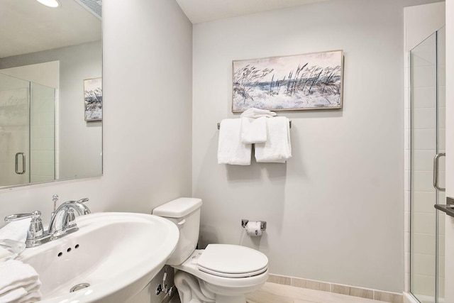 bathroom featuring toilet, sink, and a shower with shower door