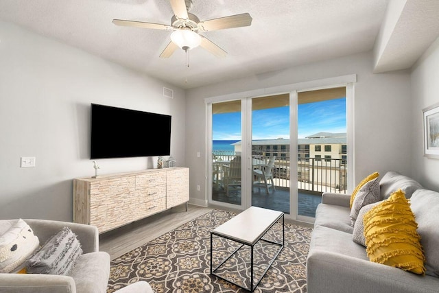 living room with hardwood / wood-style floors, a textured ceiling, and ceiling fan