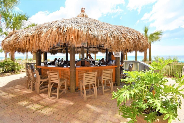 view of patio with a gazebo, exterior bar, and a water view