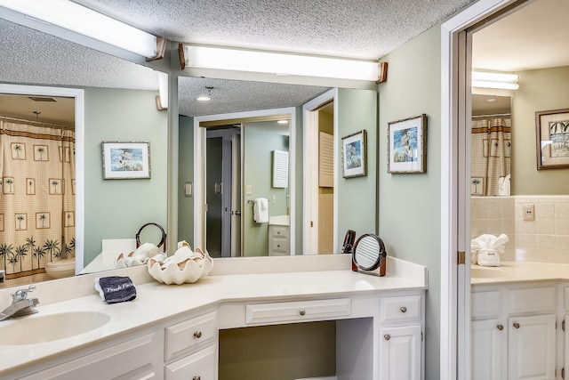 bathroom featuring backsplash, vanity, a textured ceiling, and toilet