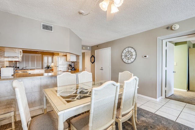 dining space featuring a textured ceiling, light tile patterned floors, and ceiling fan