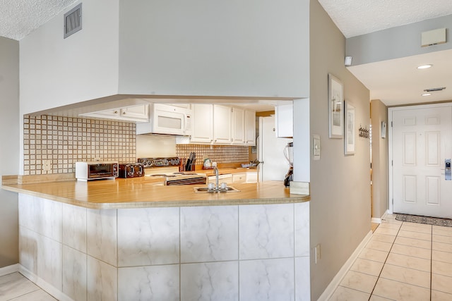 kitchen featuring gas range oven, a textured ceiling, and light tile patterned flooring