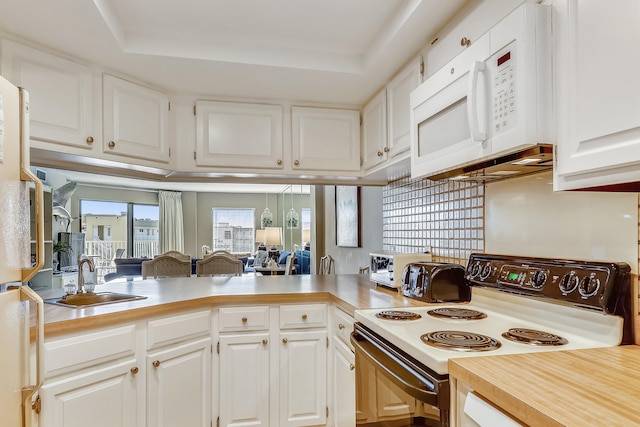 kitchen with white cabinetry, kitchen peninsula, and white appliances