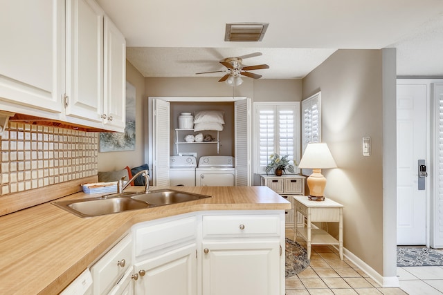 kitchen featuring light tile patterned flooring, sink, a textured ceiling, washing machine and clothes dryer, and white cabinets