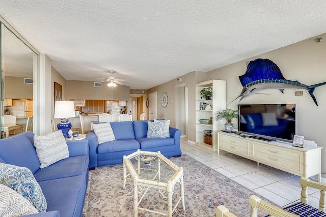 living room with a textured ceiling, ceiling fan, and light tile patterned floors