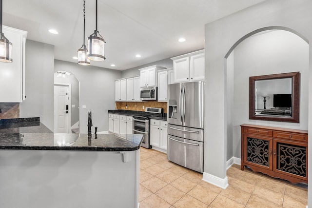 kitchen featuring light tile patterned flooring, backsplash, stainless steel appliances, pendant lighting, and white cabinets